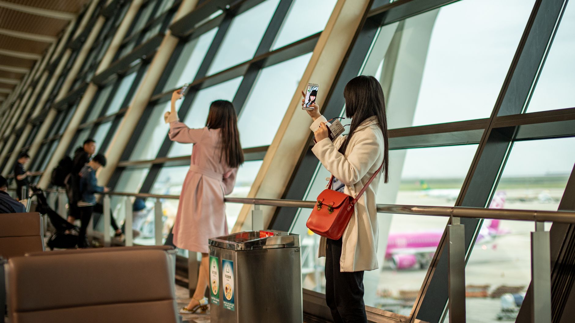 Airline passenger using a smartphone to manage a flight booking in an airport terminal