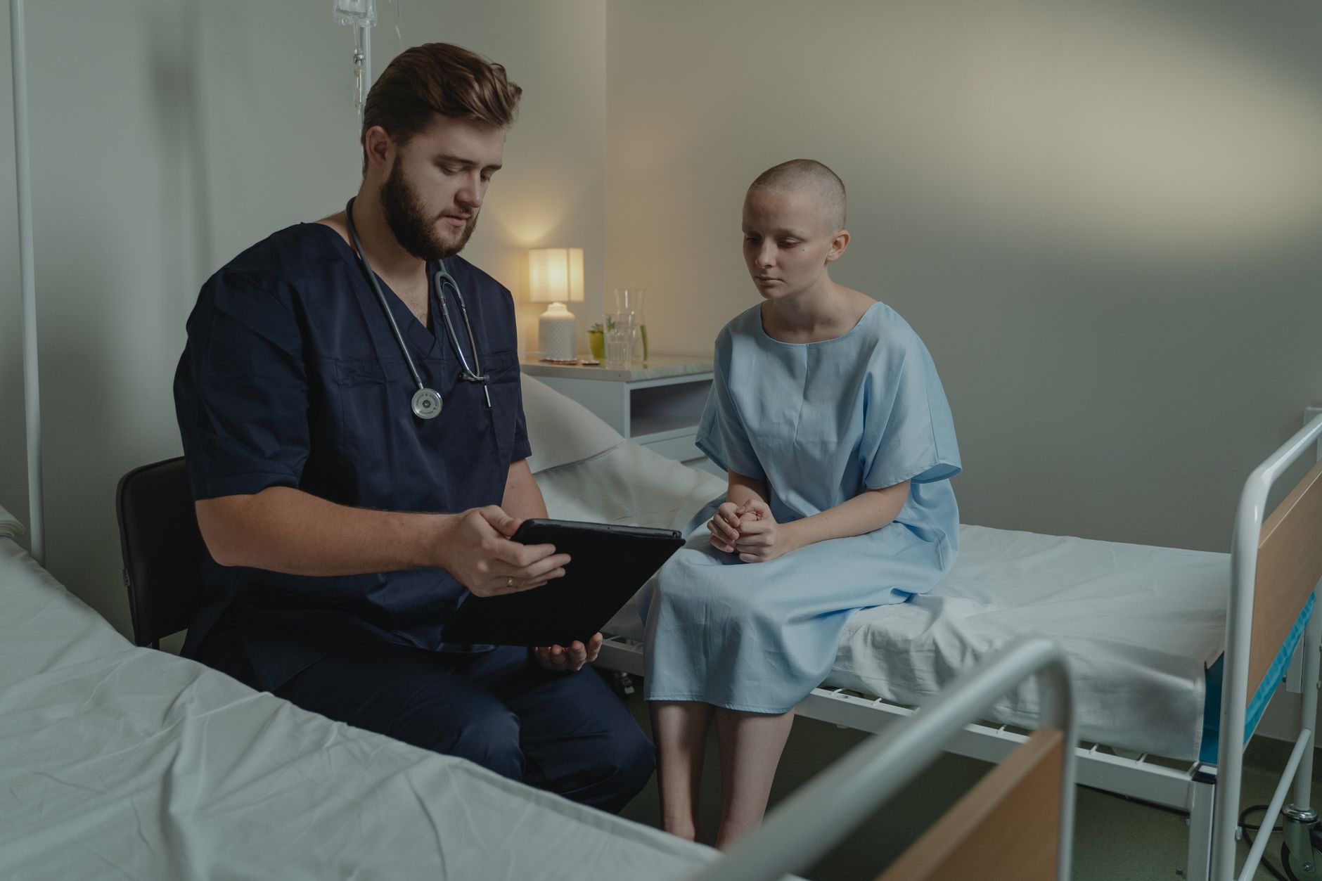Clinician helping a patient use a tablet to access a patient portal in a hospital setting