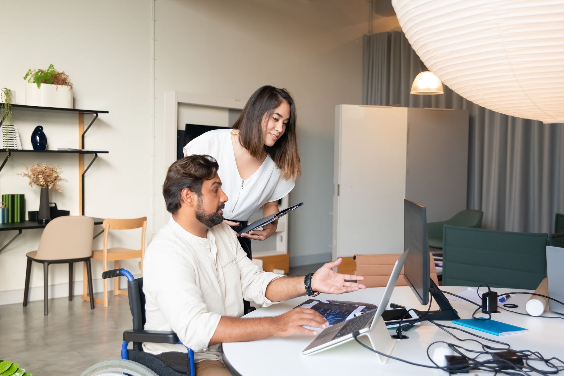 Person checking health metrics on a smartwatch while using a laptop in a bright workspace