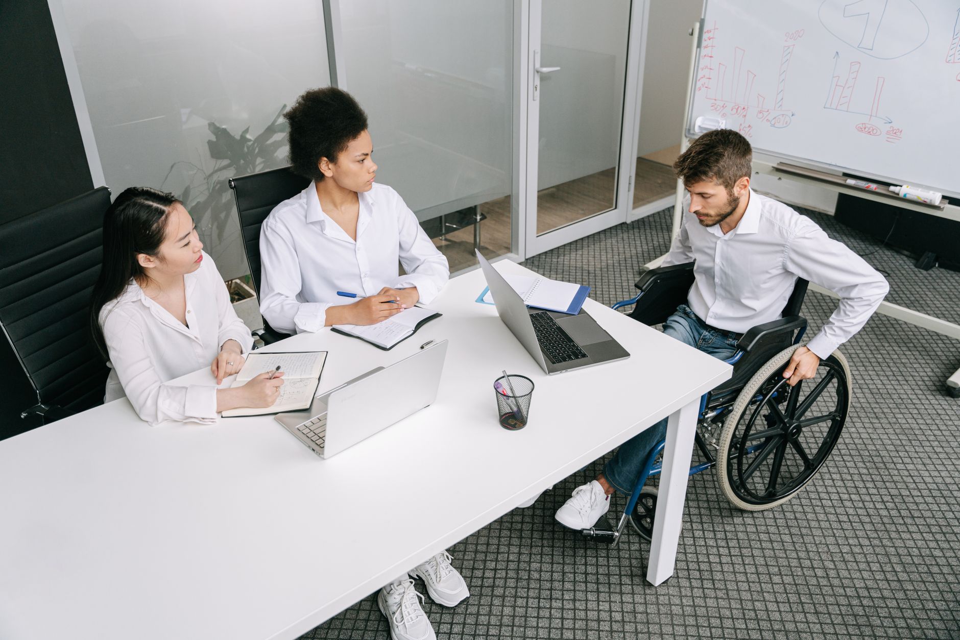Diverse team reviewing an accessible Pride Month webpage on a laptop with color contrast and captions visible