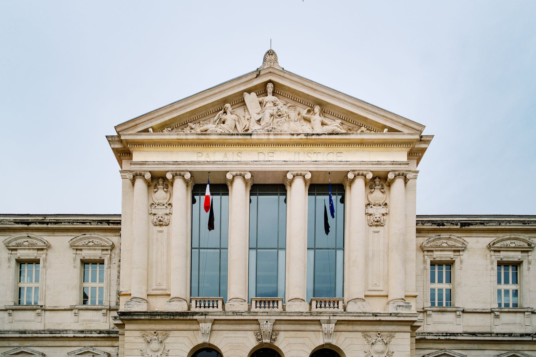 European courthouse exterior with EU flag and people walking past, representing EAA enforcement and accessibility litigation