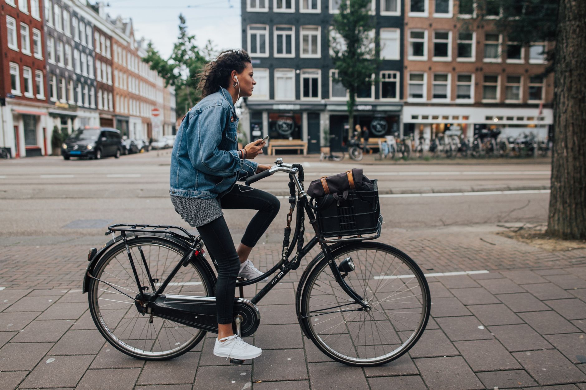Cyclist using a smartphone in a modern Dutch city street with accessible signage in the background