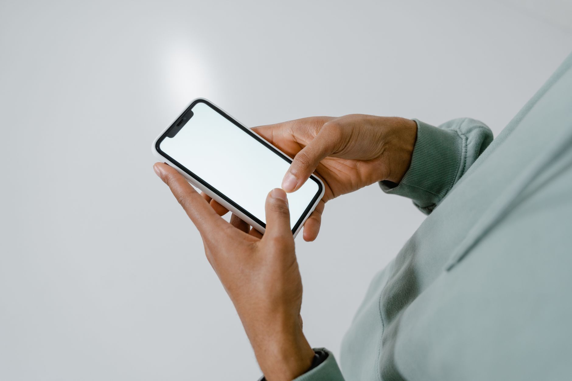 Mobile app developer reviewing accessibility checklist on a smartphone next to a laptop