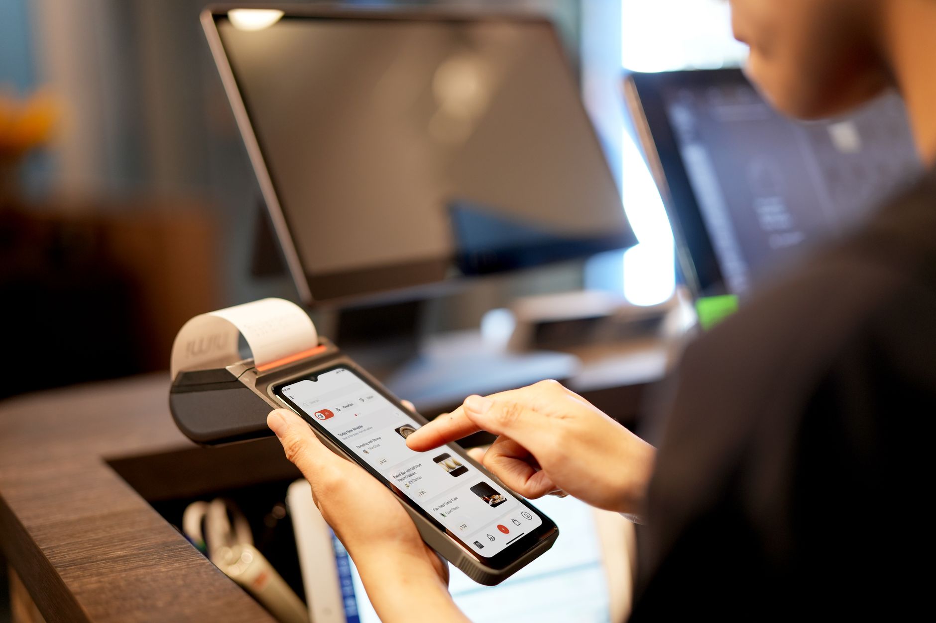 Person paying online with a laptop and a smartphone on a desk, showing multiple payment options